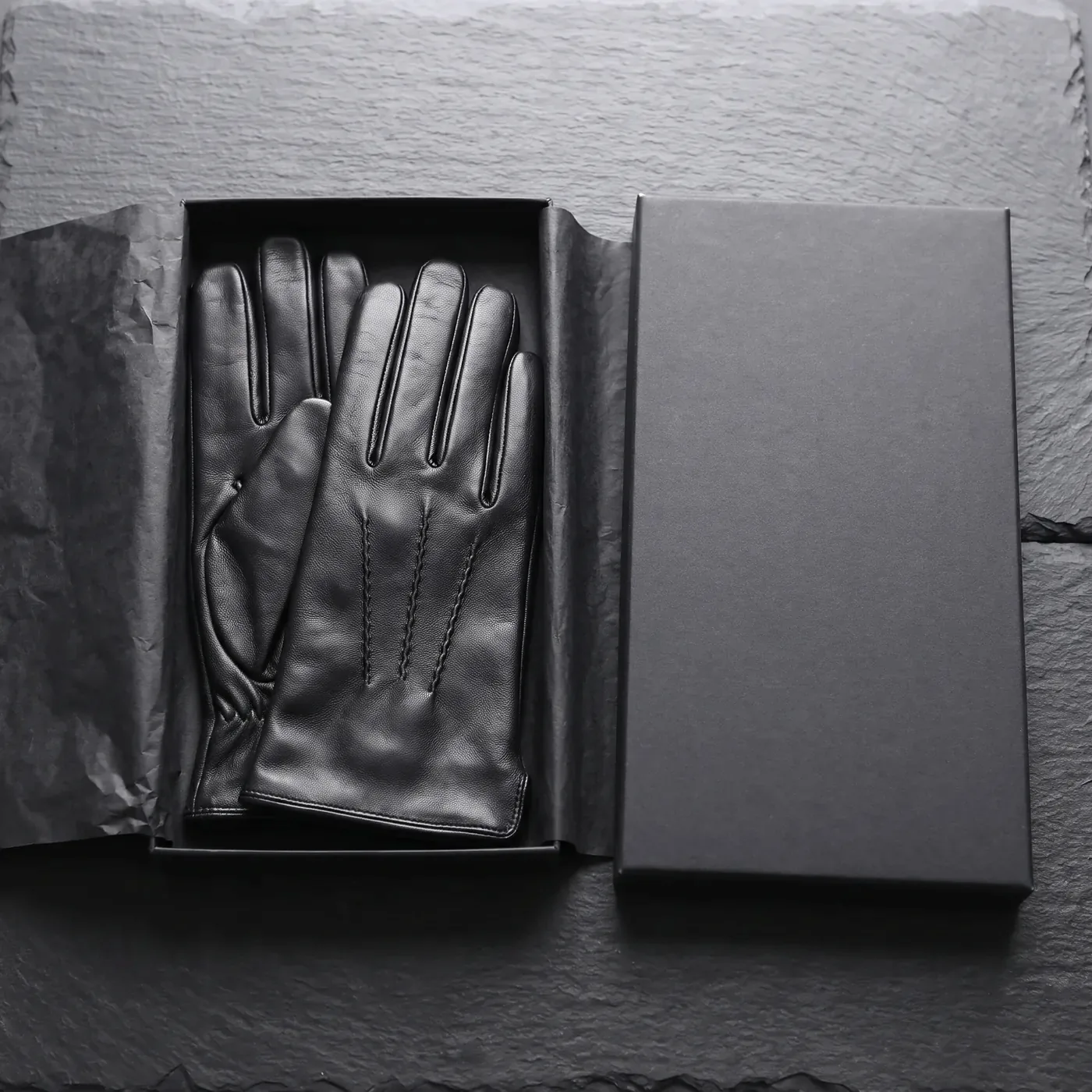 Black leather dress gloves folded in a plain black gift box with black tissue